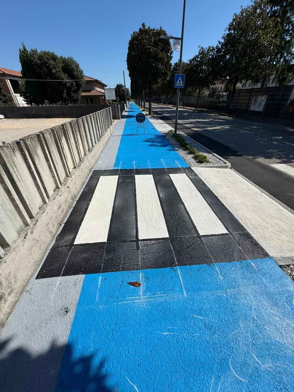 Marciapiede pedonale blu e grigio con attraversamento pedonale.