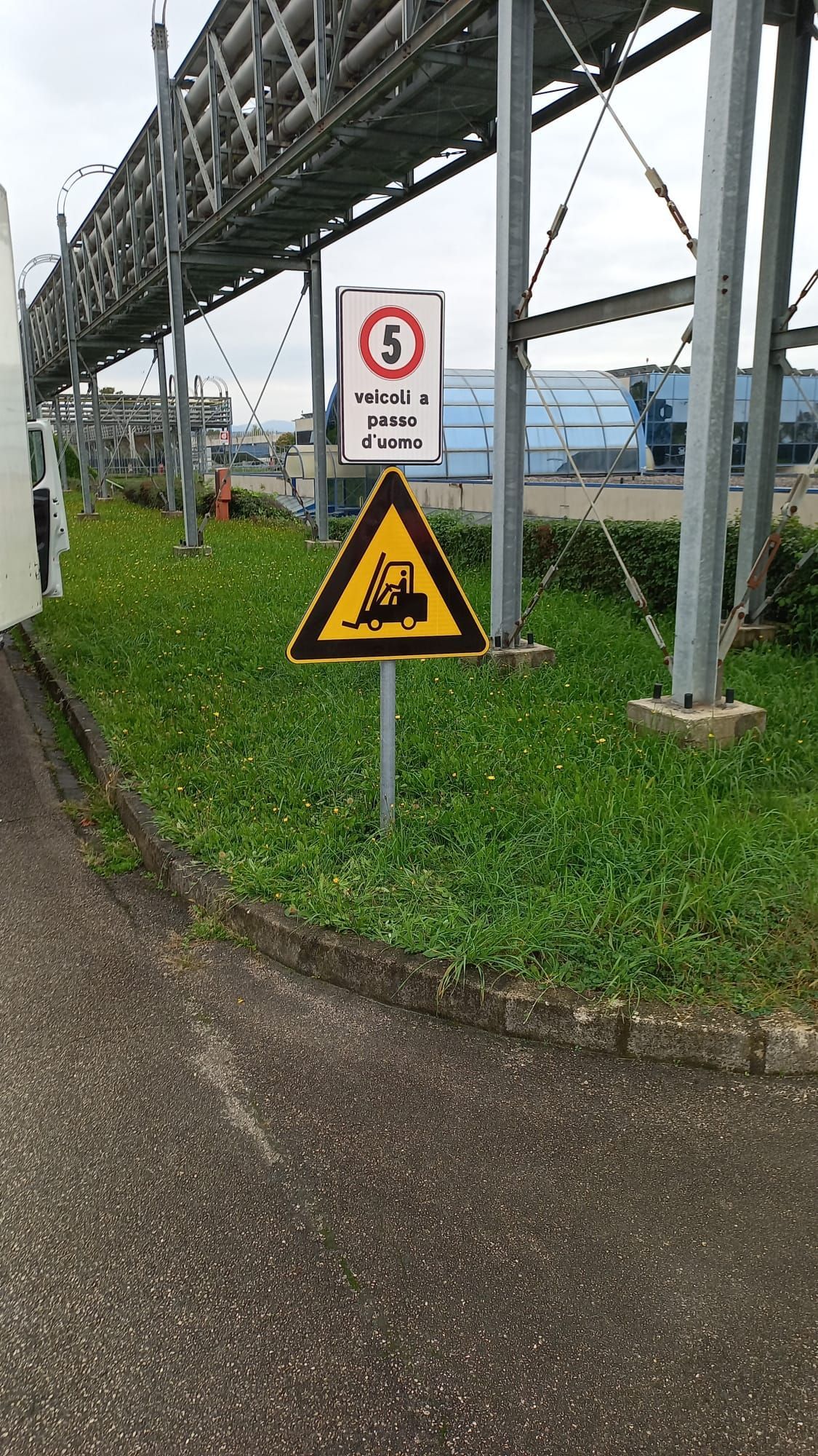 Segnali di limite di velocità e di attraversamento ferroviario su un'area erbosa. Contesto industriale.