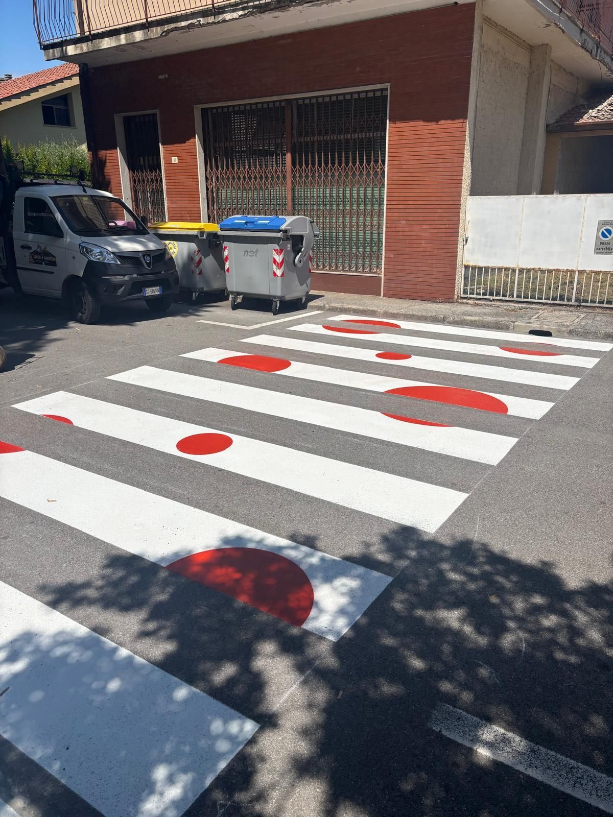 Attraversamento pedonale con cerchi rossi dipinti su strisce bianche