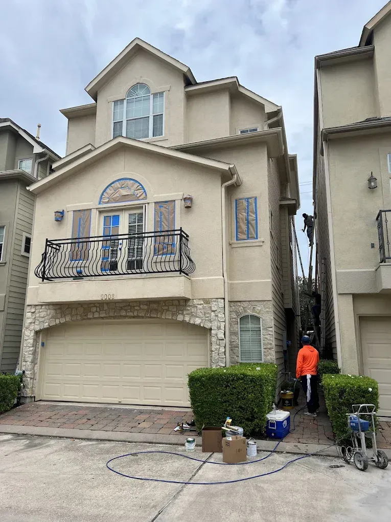 Beige multi-story townhouse with a garage and a wrought iron balcony.