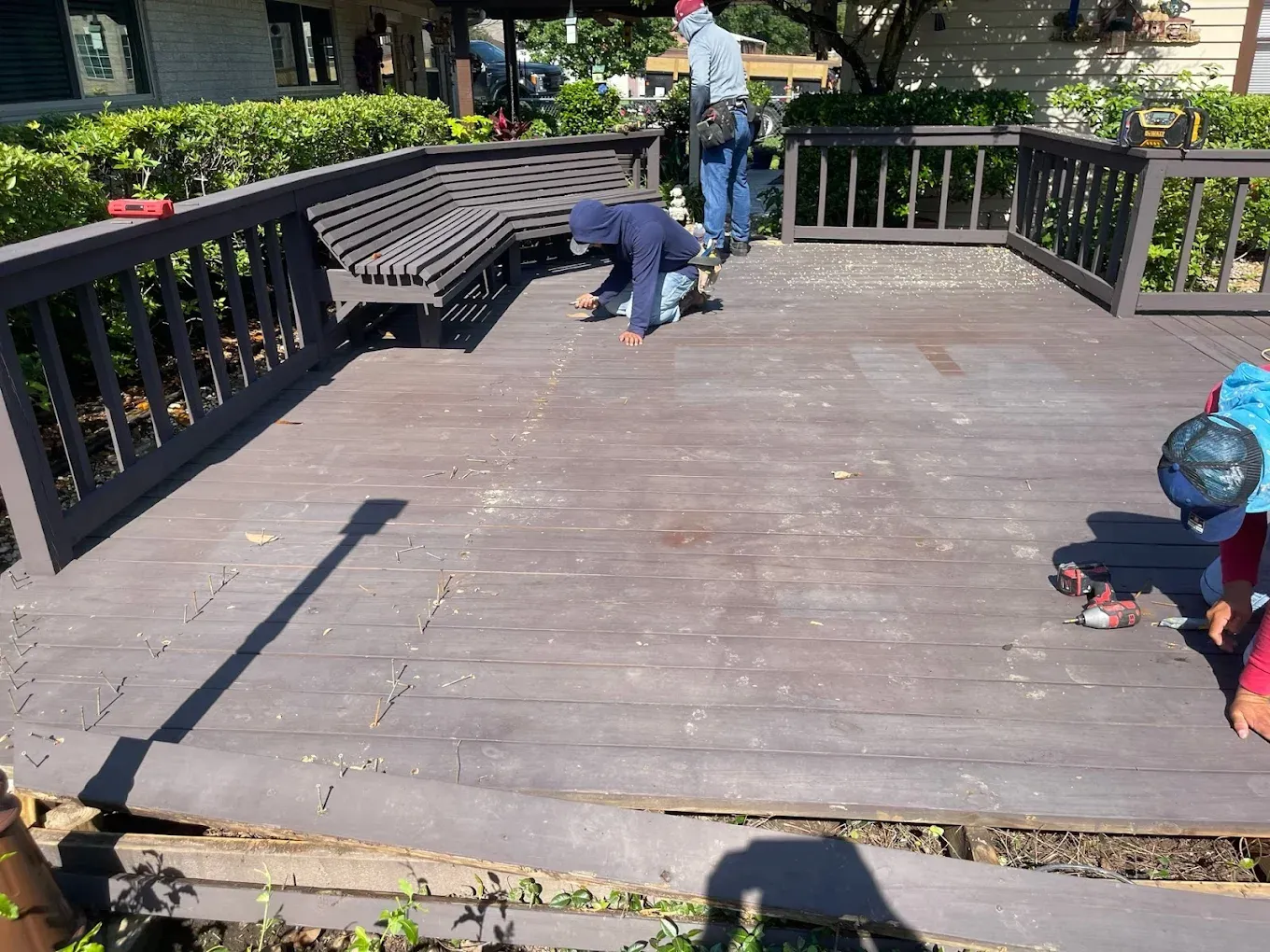 Workers renovating a wooden deck.