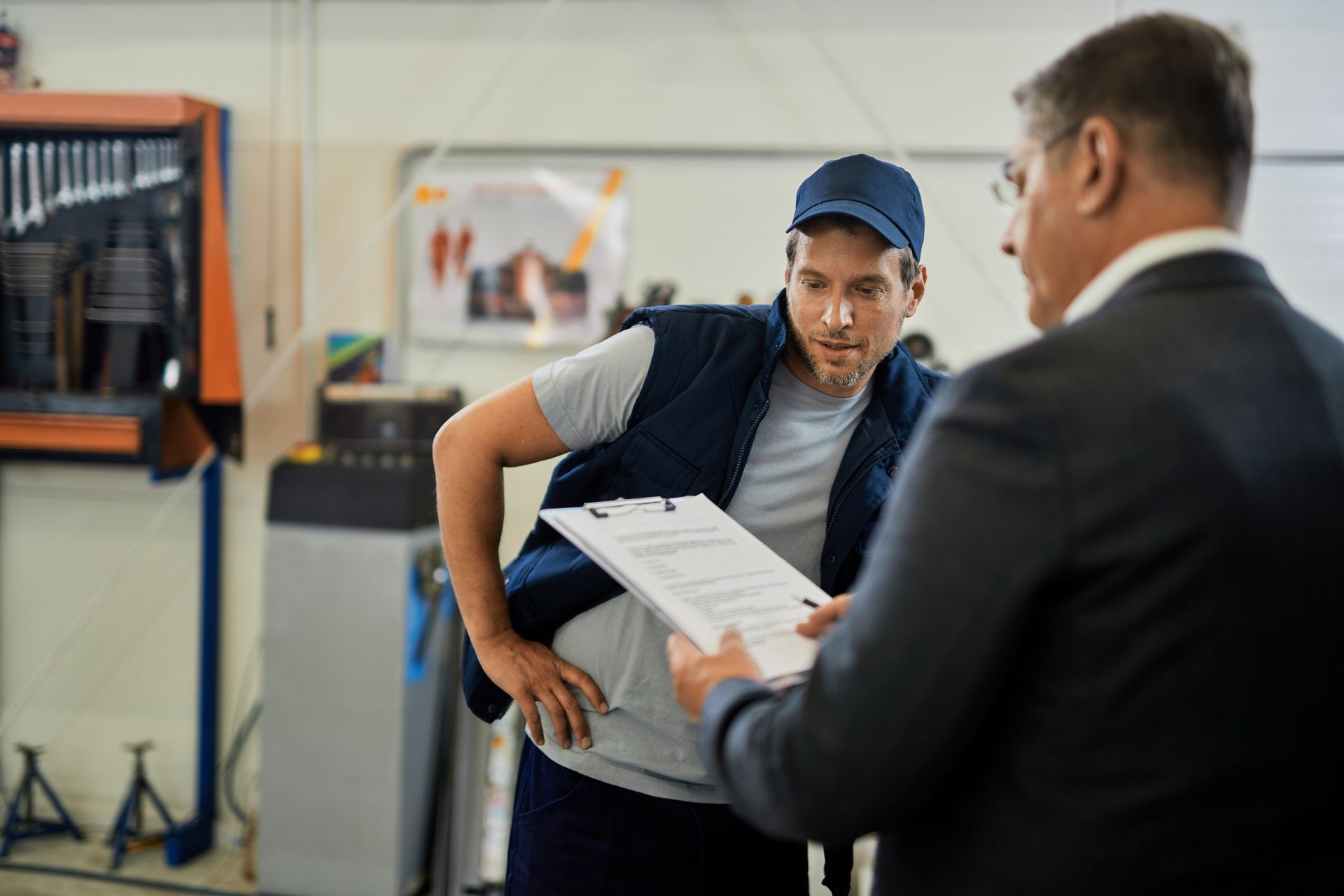 a man in a suit is giving a man a clipboard in a garage .