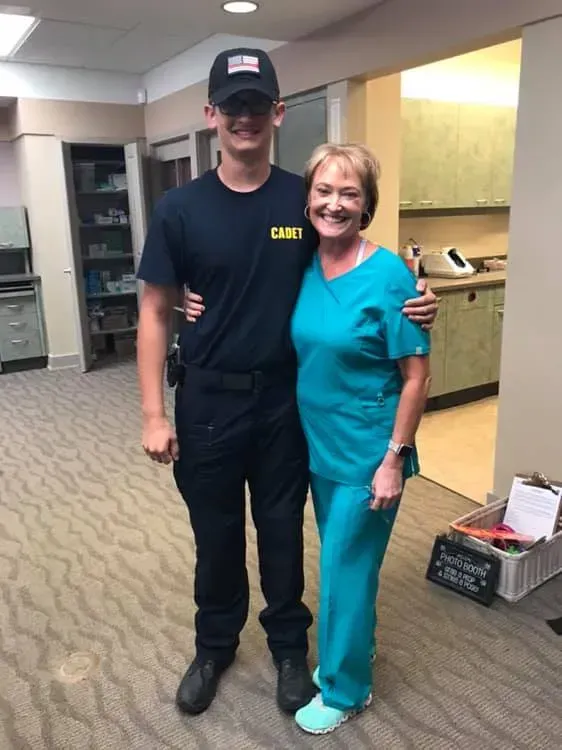 A man in a camo shirt stands next to a woman in scrubs