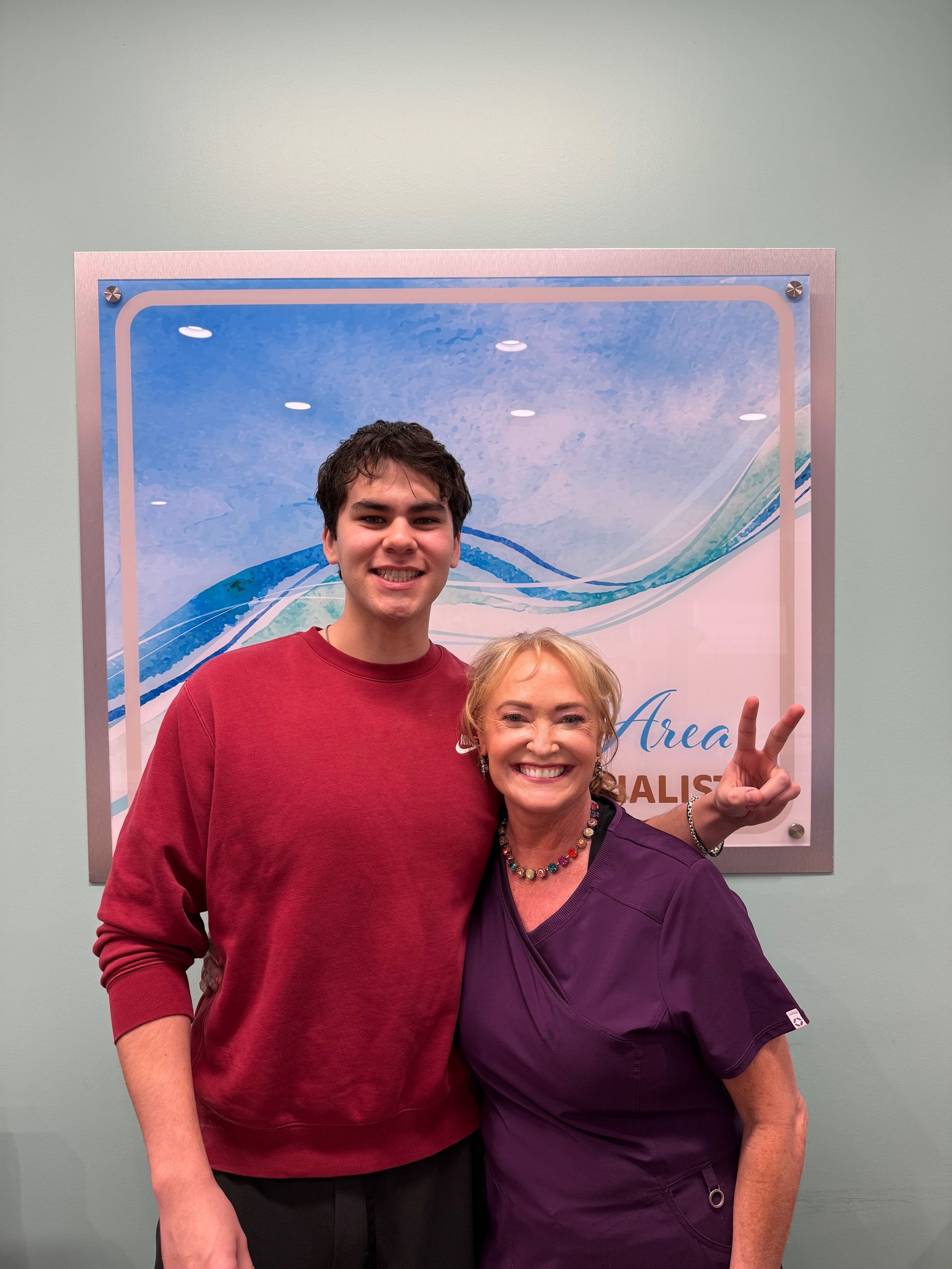 A man and a woman are posing for a picture in front of a sign.