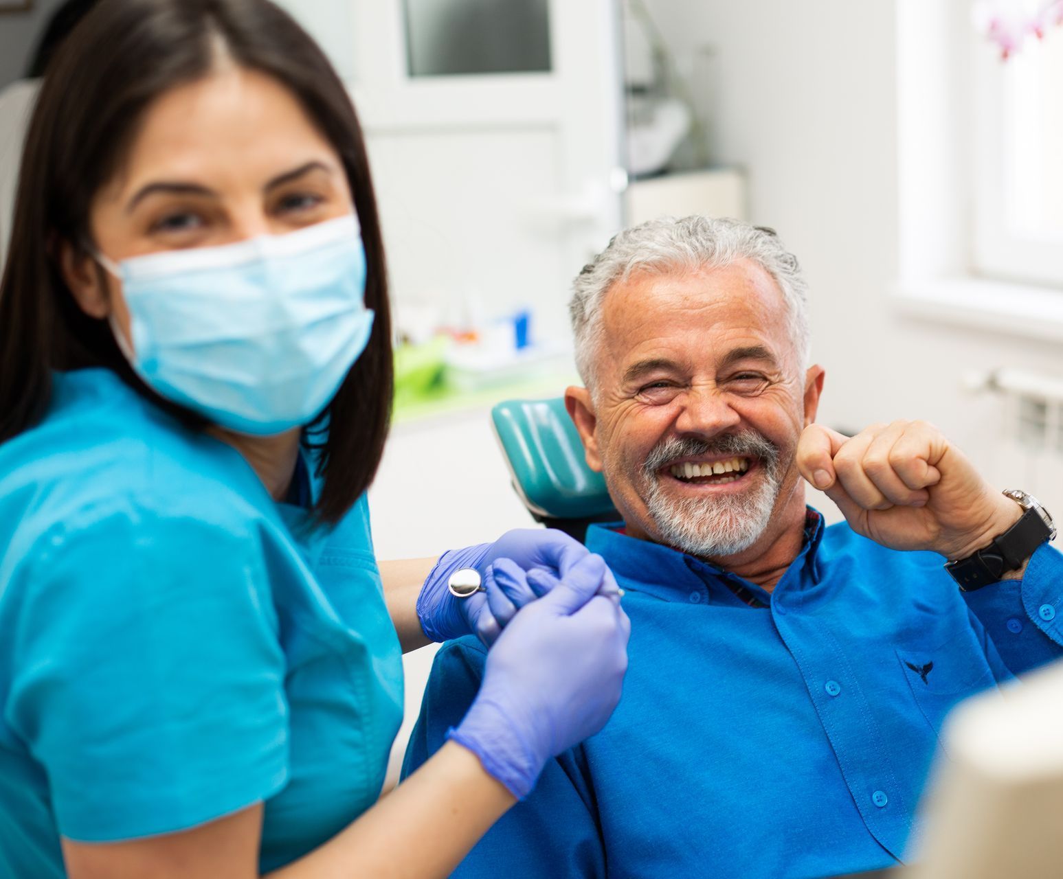 A man is sitting in a dental chair talking to a dentist.