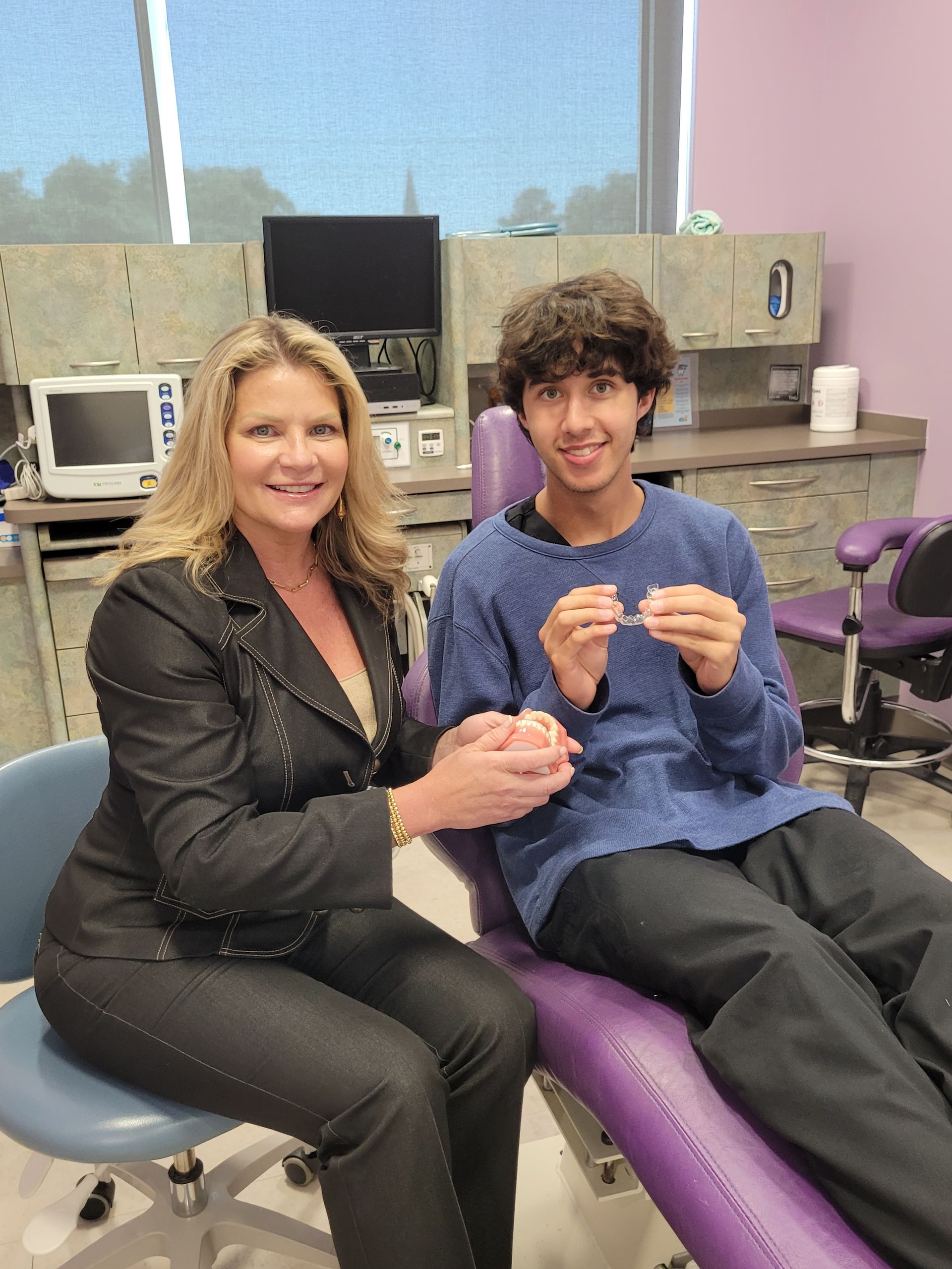 A woman is sitting next to a boy in a dental chair