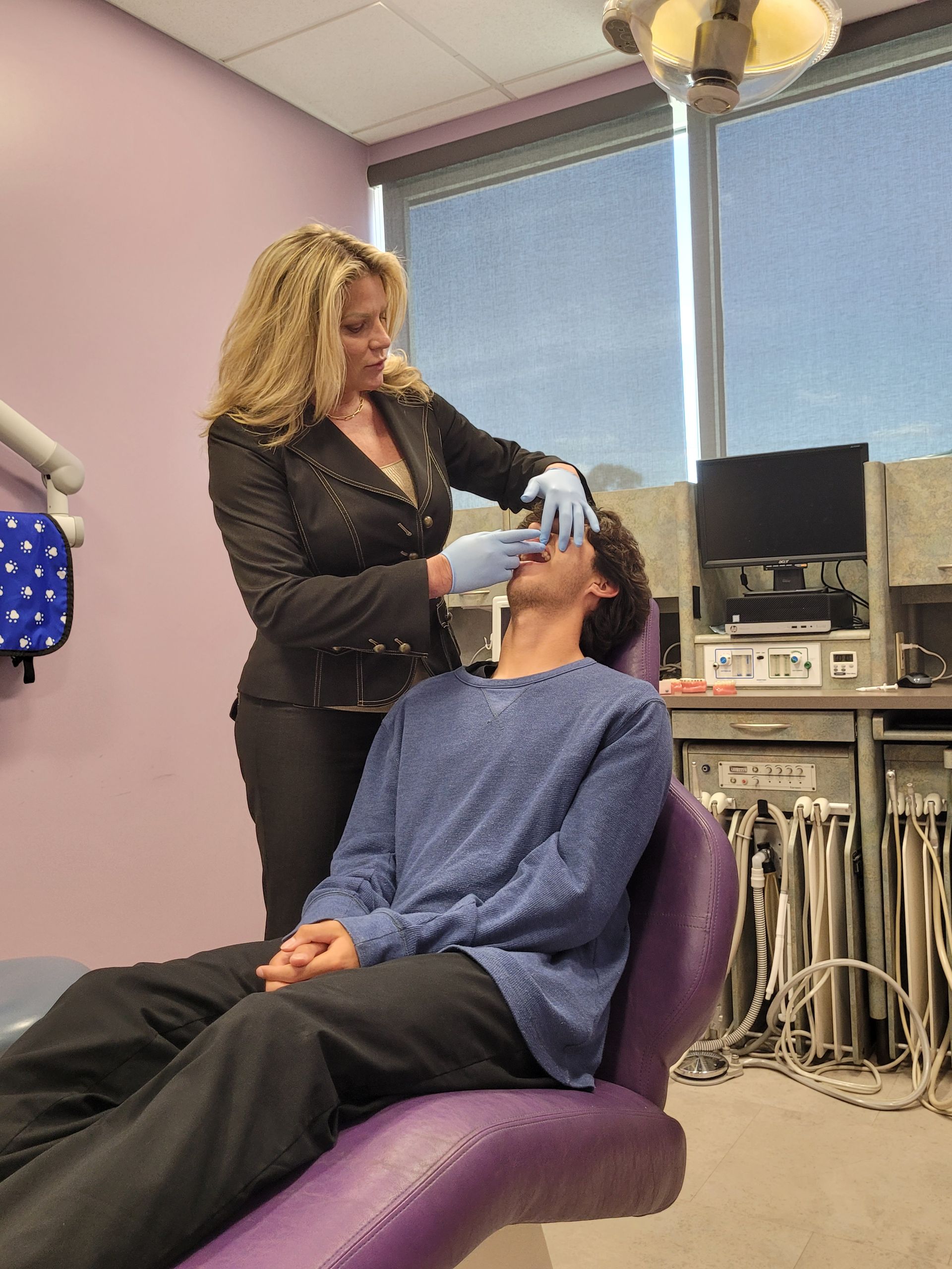 A woman is examining a man 's teeth in a dental office.