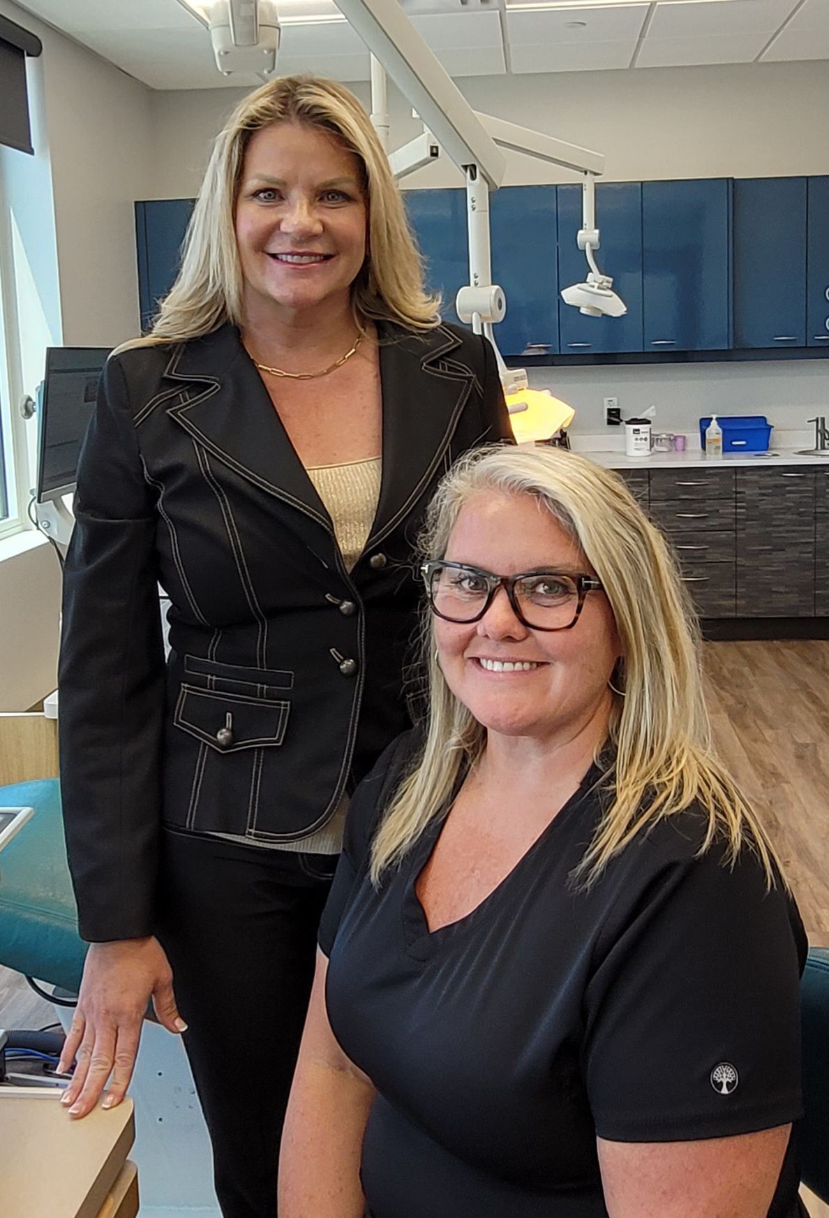Two women are standing next to each other in a dental office.
