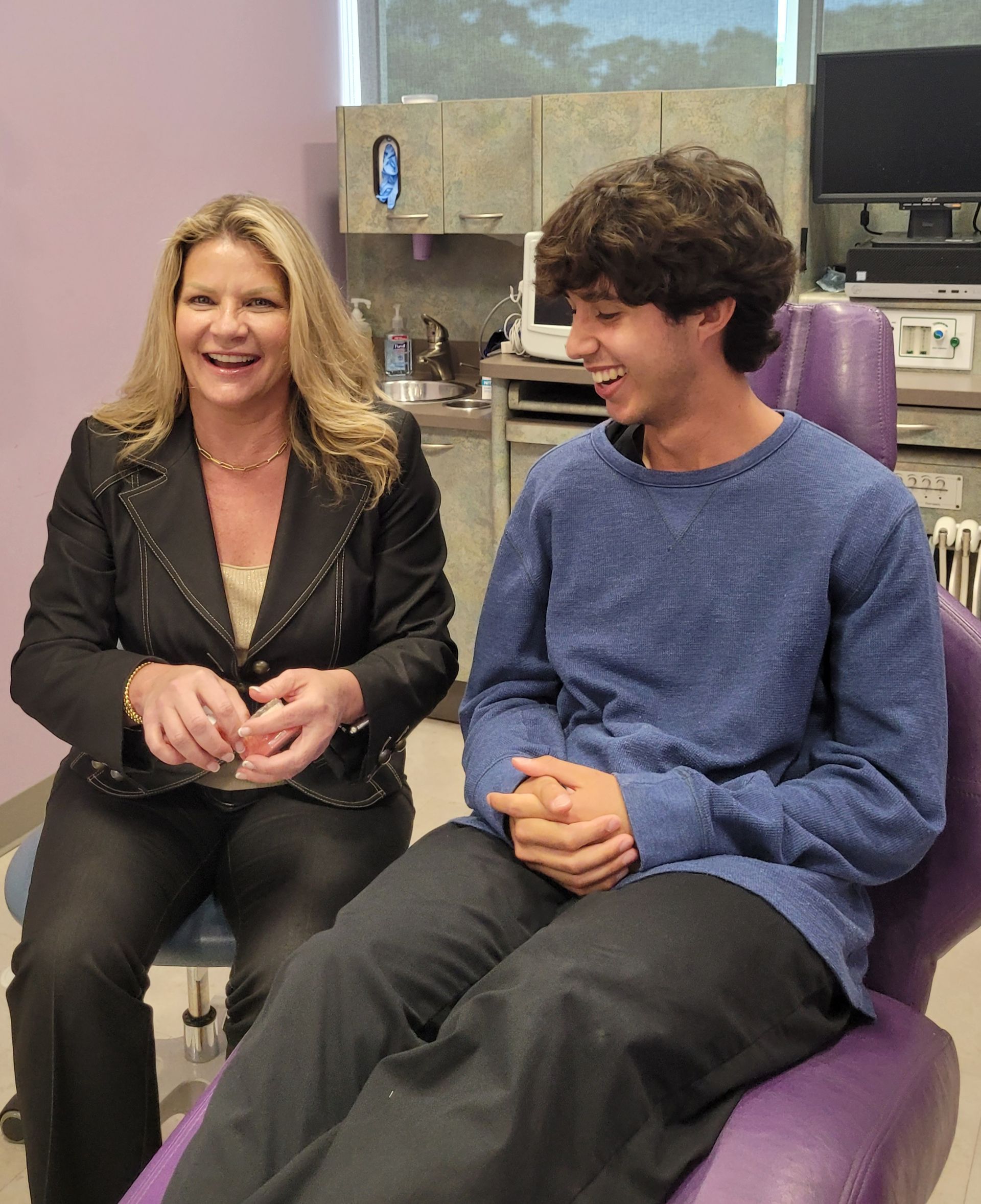 A woman is sitting next to a boy in a dental chair