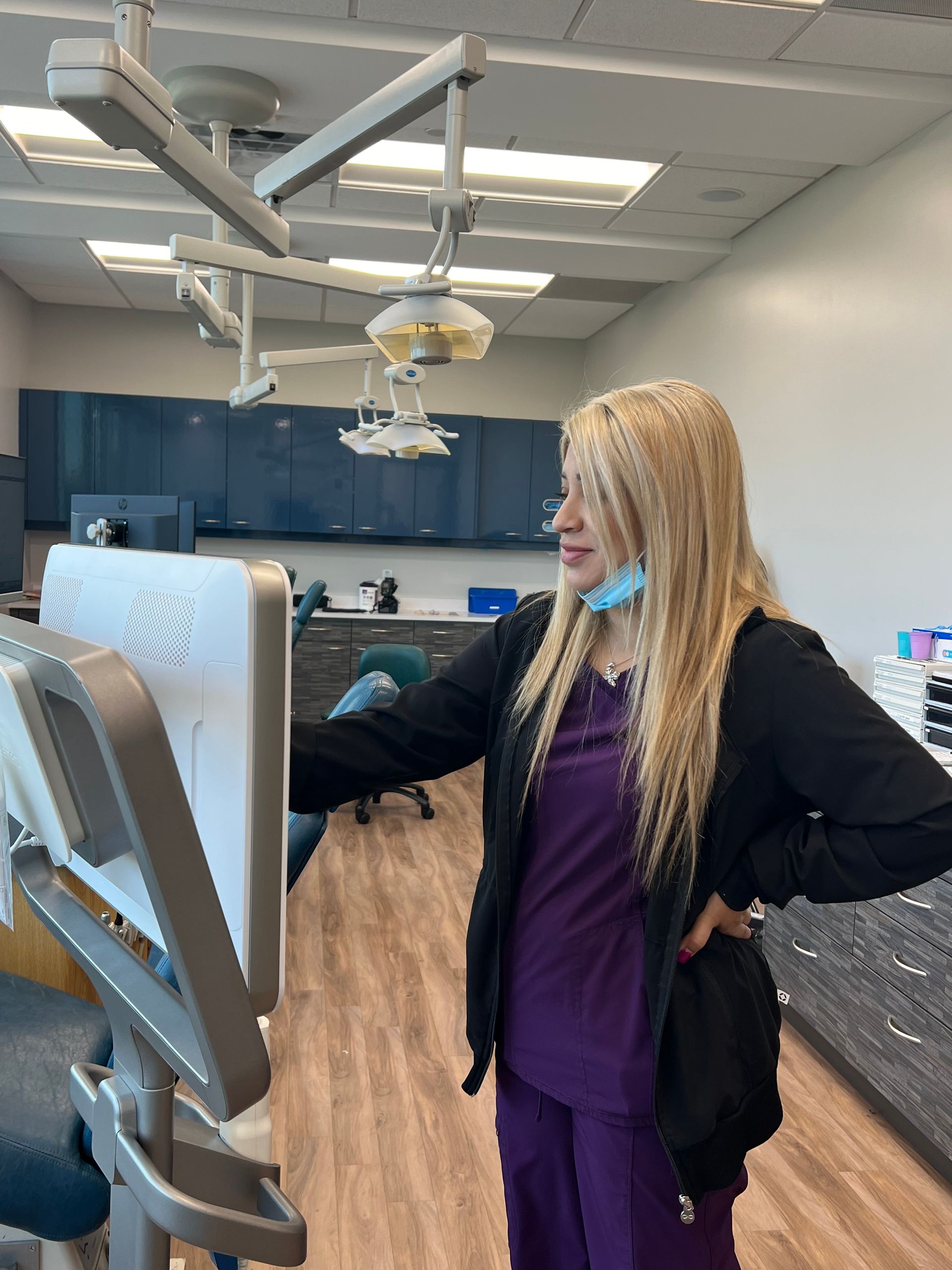 A woman is standing in front of a computer in a dental office.
