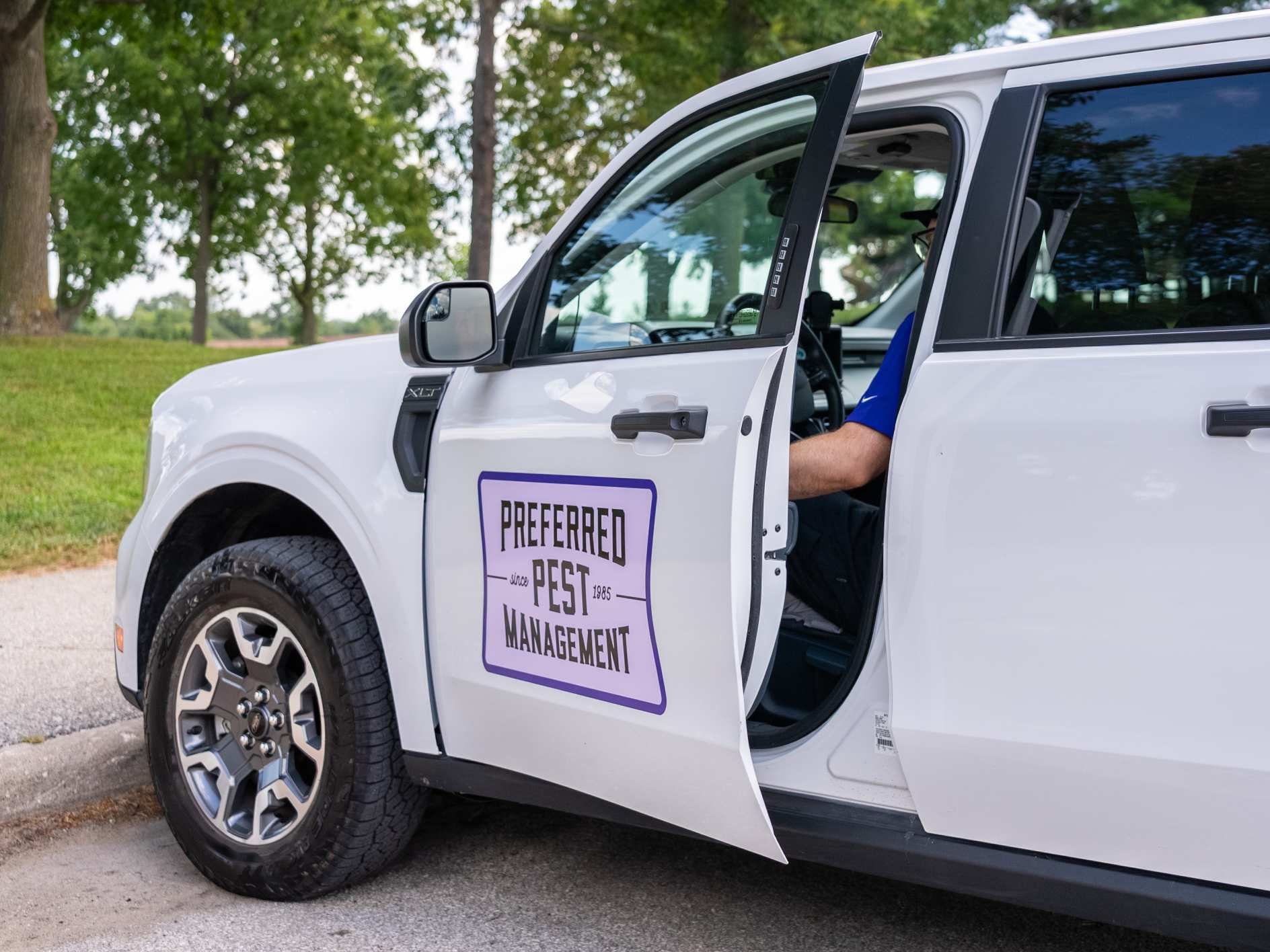 White pest control truck with open door and company sign.