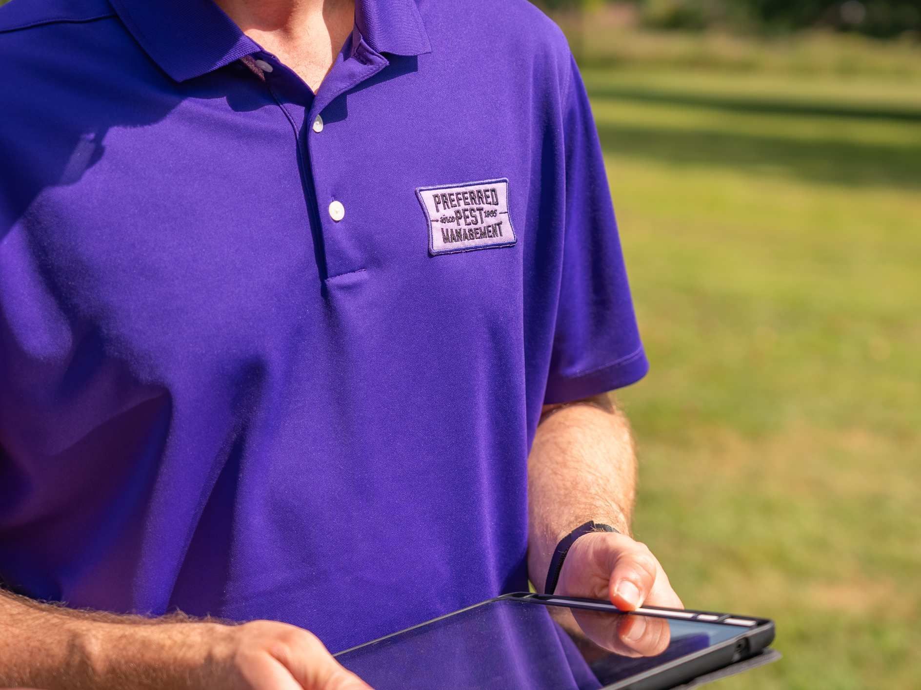 Man in purple polo shirt holding tablet, with logo 