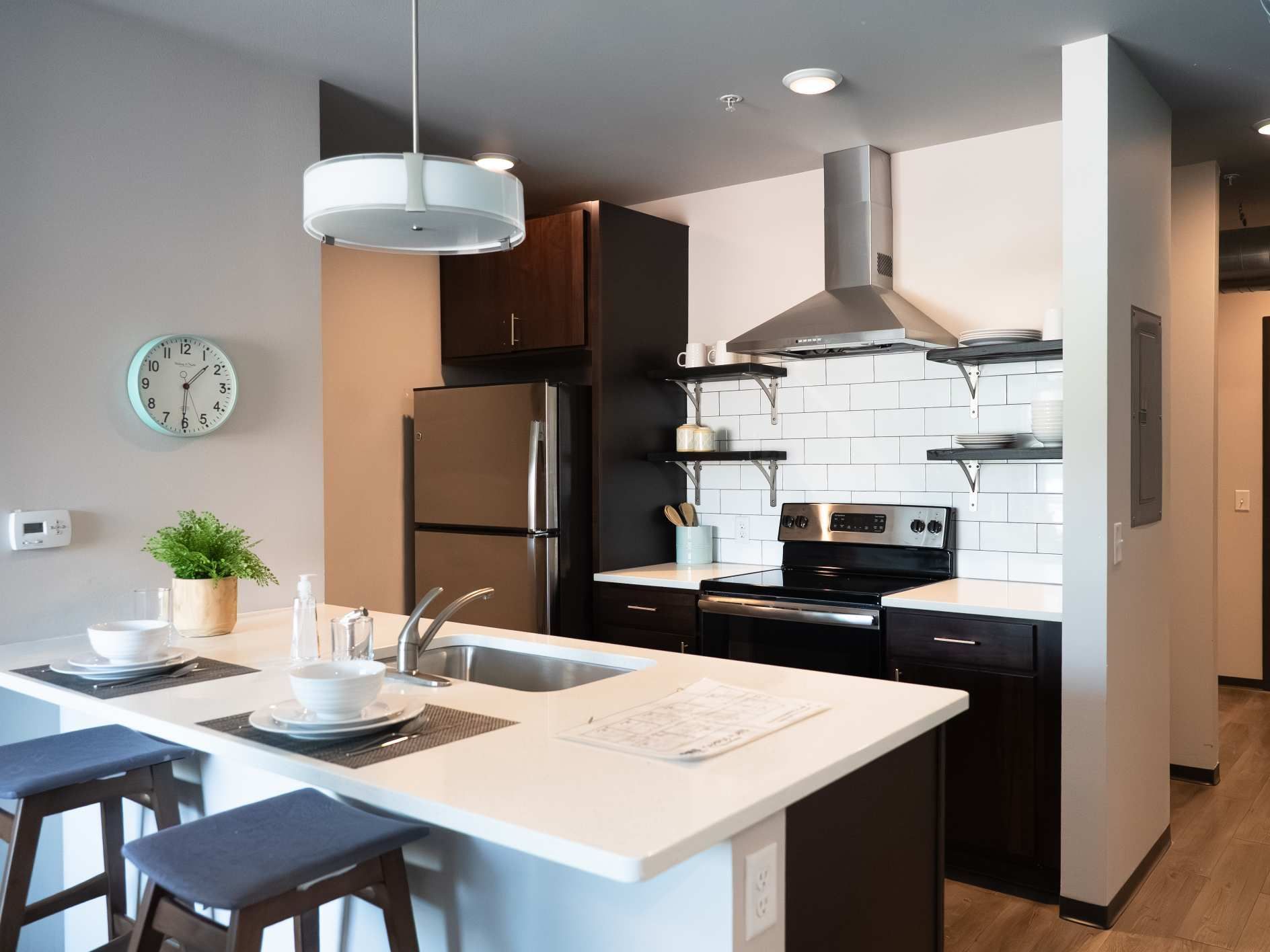 Modern kitchen with island, stainless steel appliances, and dark cabinetry.