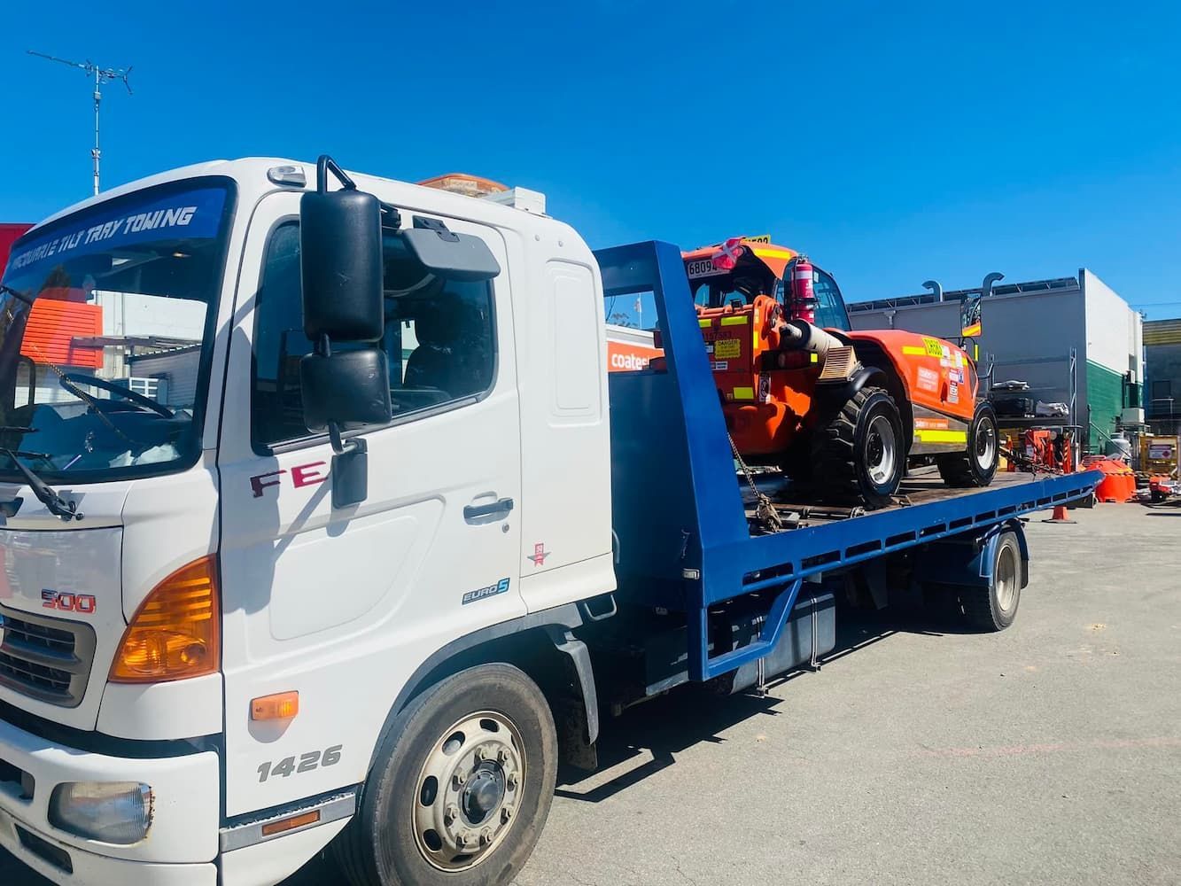 Truck Carrying Orange Tractor — Port Macquarie Tilt Tray Towing in Kempsey, NSW