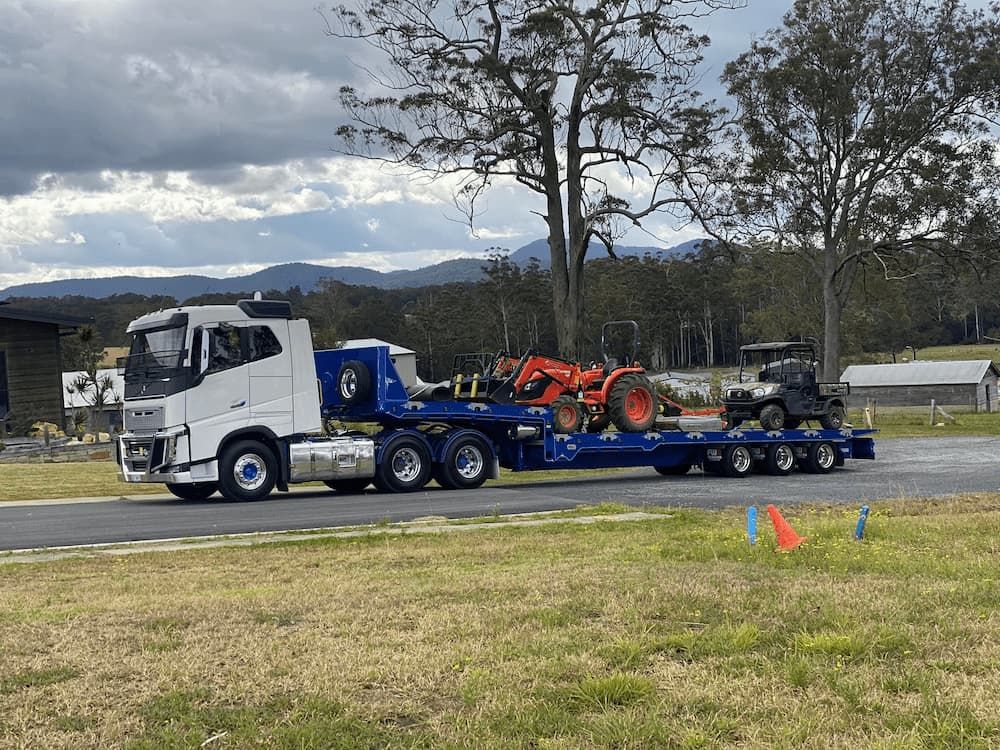 Large Tow Truck Hauling Two Pieces of Heavy Equipment — Port Macquarie Tilt Tray Towing in Telegraph Point, NSW