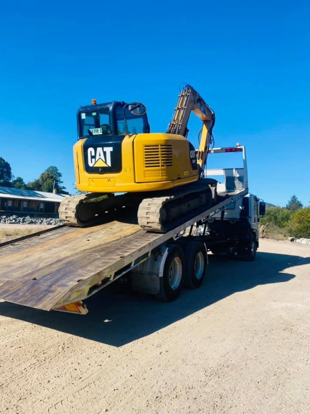 A Yellow Cat Excavator is on a Flatbed Truck — Port Macquarie Tilt Tray Towing in Coffs Harbour, NSW
