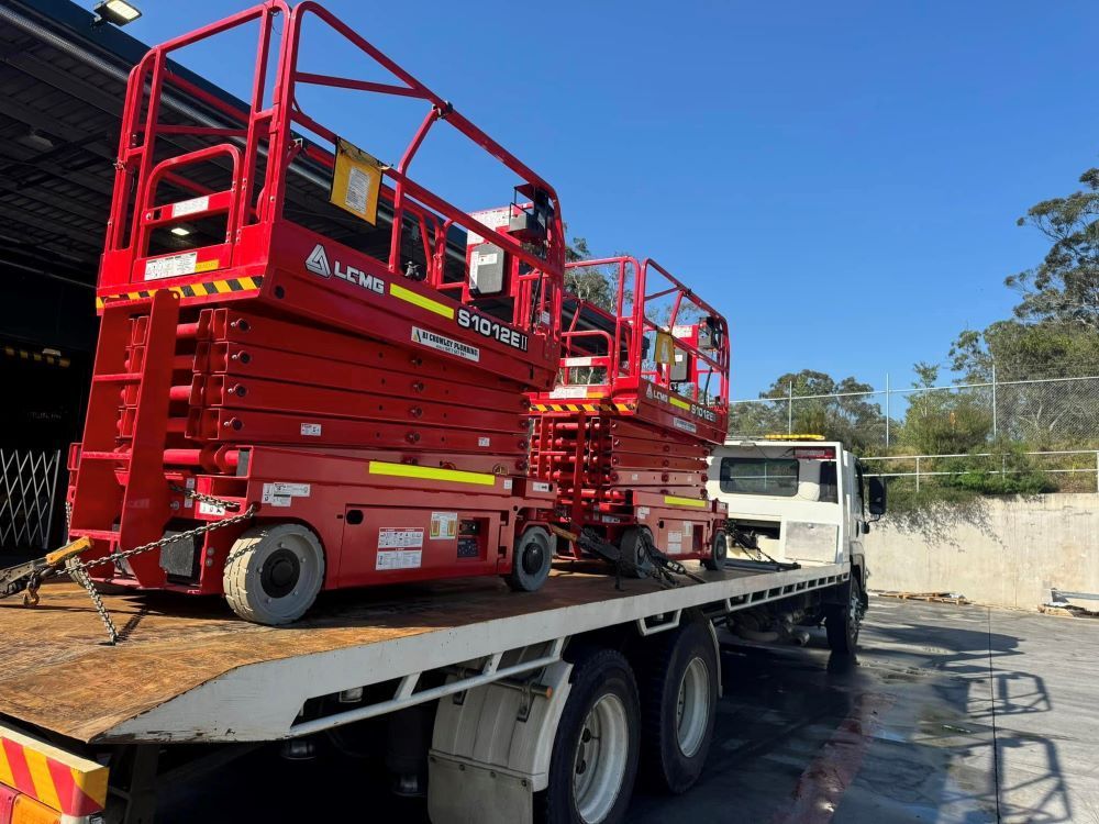 Two Red Scissor Lifts Are Sitting on Top of a Flatbed Truck — Port Macquarie Tilt Tray Towing in Newcastle, NSW