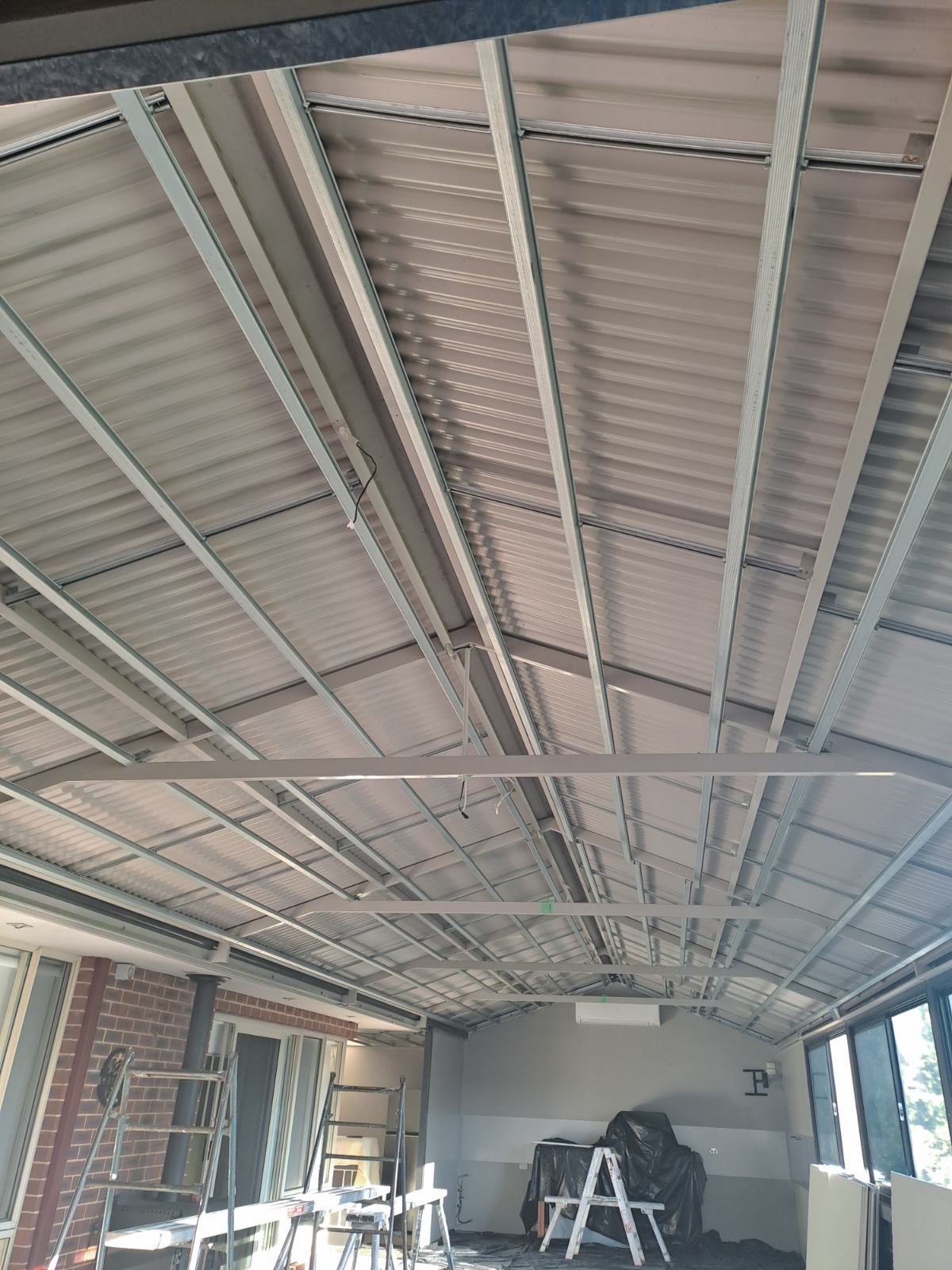 The ceiling of a building with a ladder in the middle of it.