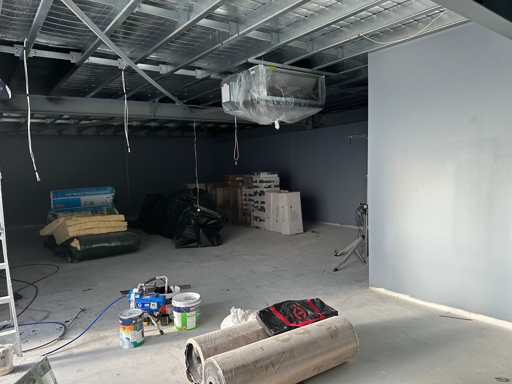 An empty room with a ceiling fan hanging from it.