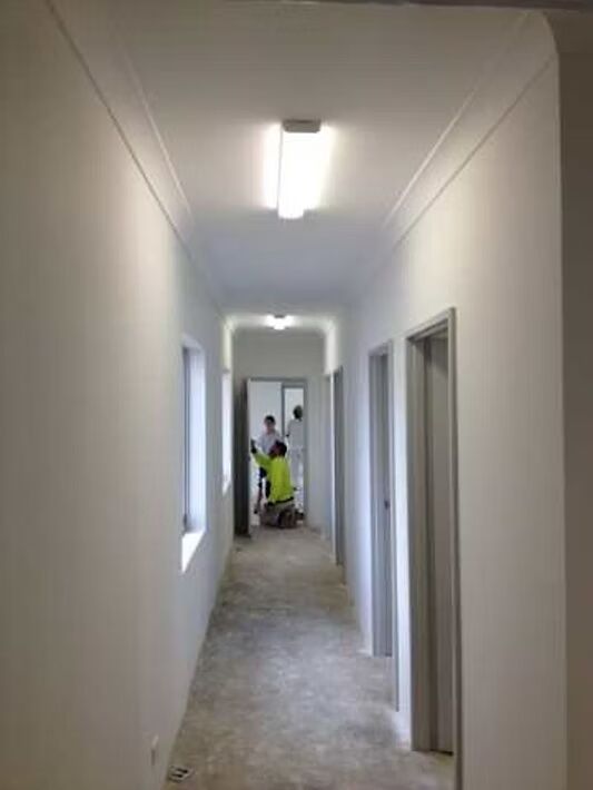 A long hallway with white walls and a light on the ceiling.