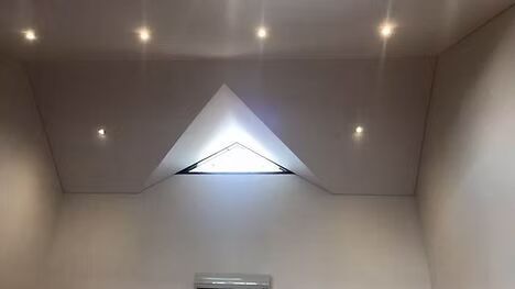 A room with a triangle window in the ceiling.