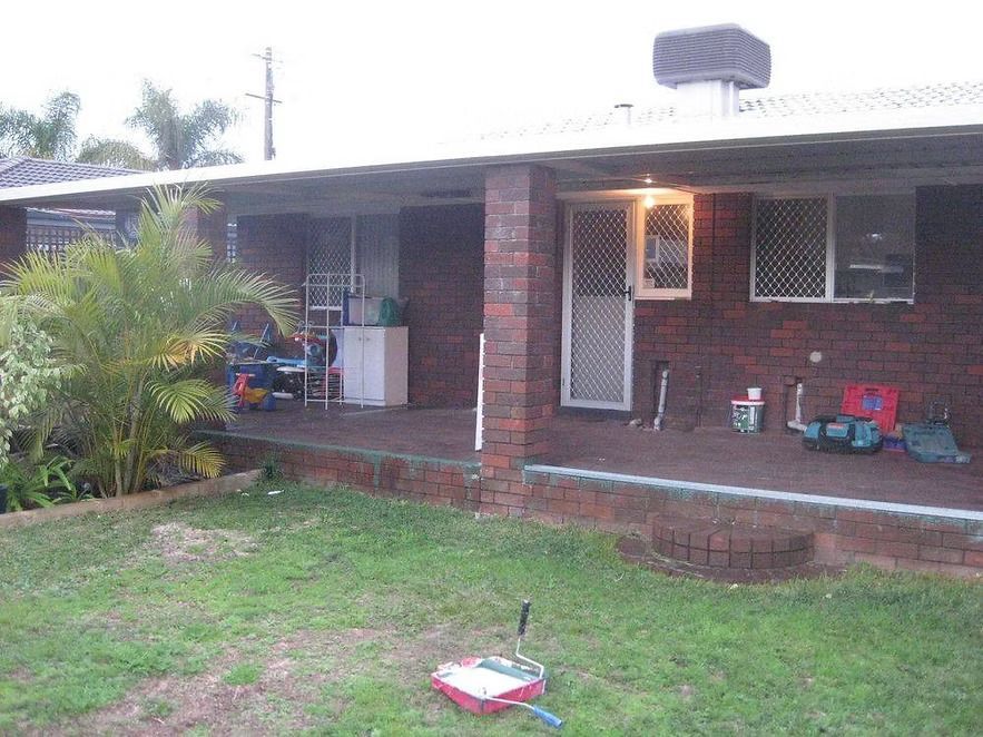 A brick house with a porch and a lawn mower in front of it.