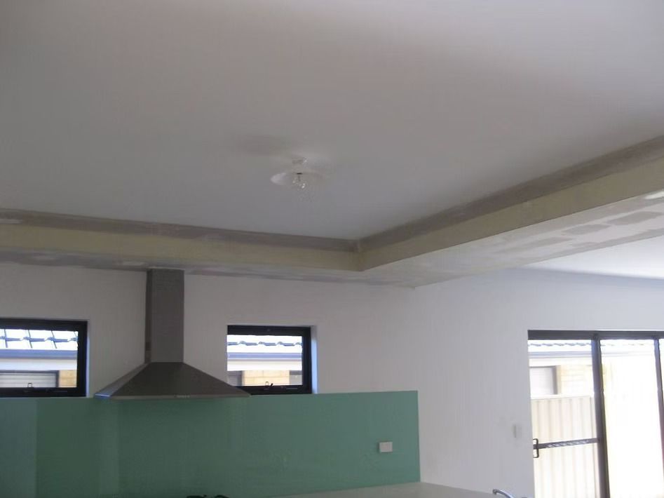 A kitchen with white walls and a stainless steel hood