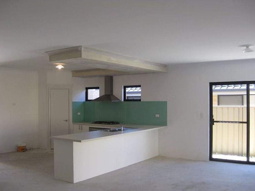 An empty kitchen with a stove top oven and sliding glass doors