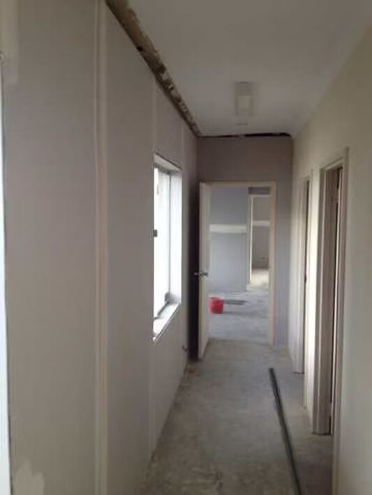 A long hallway with a door and windows in a house under construction.