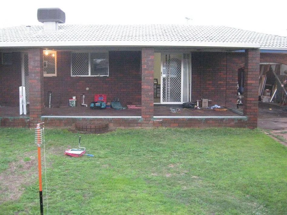 A brick house with a porch and a lawn in front of it.