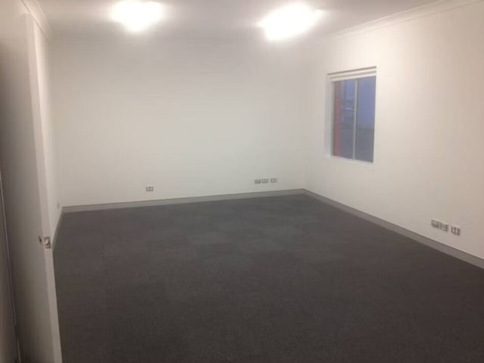 An empty room with a window and a carpeted floor.