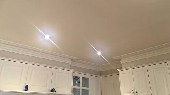 A kitchen with white cabinets and a ceiling with lights on.