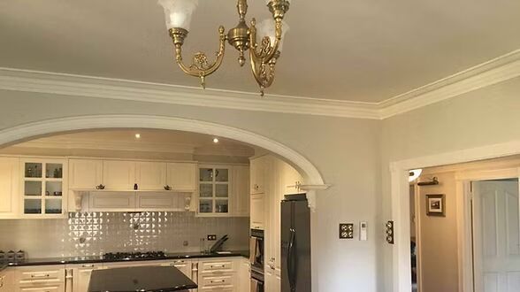 A kitchen with white cabinets and a chandelier hanging from the ceiling.