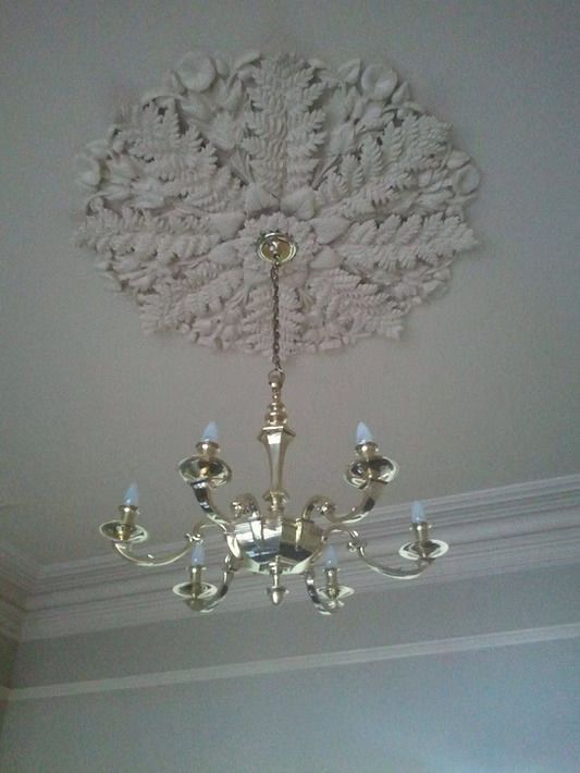 A chandelier is hanging from a ceiling with a floral design on it