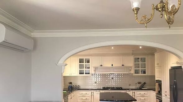 A kitchen with white cabinets and a chandelier hanging from the ceiling.