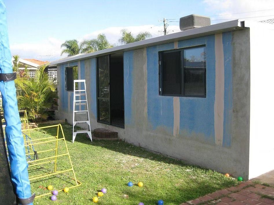 A blue and white house with a ladder in the backyard