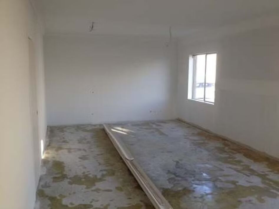 An empty room with white walls and a concrete floor.