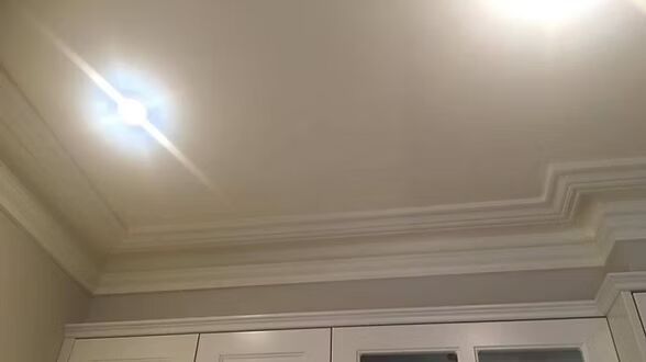A white ceiling with a light on it in a room with white cabinets.