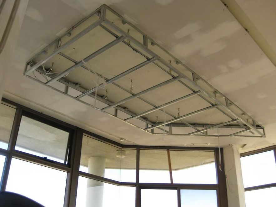 A ceiling frame is being built in a room with lots of windows