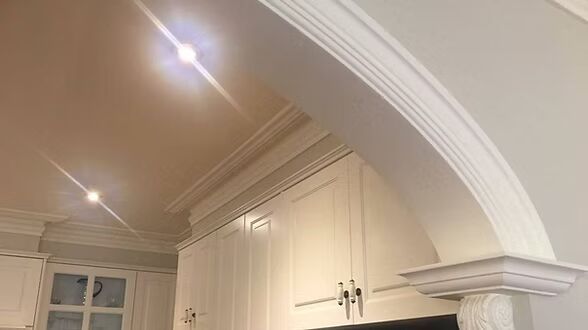 A kitchen with white cabinets , a stove , and a fireplace.