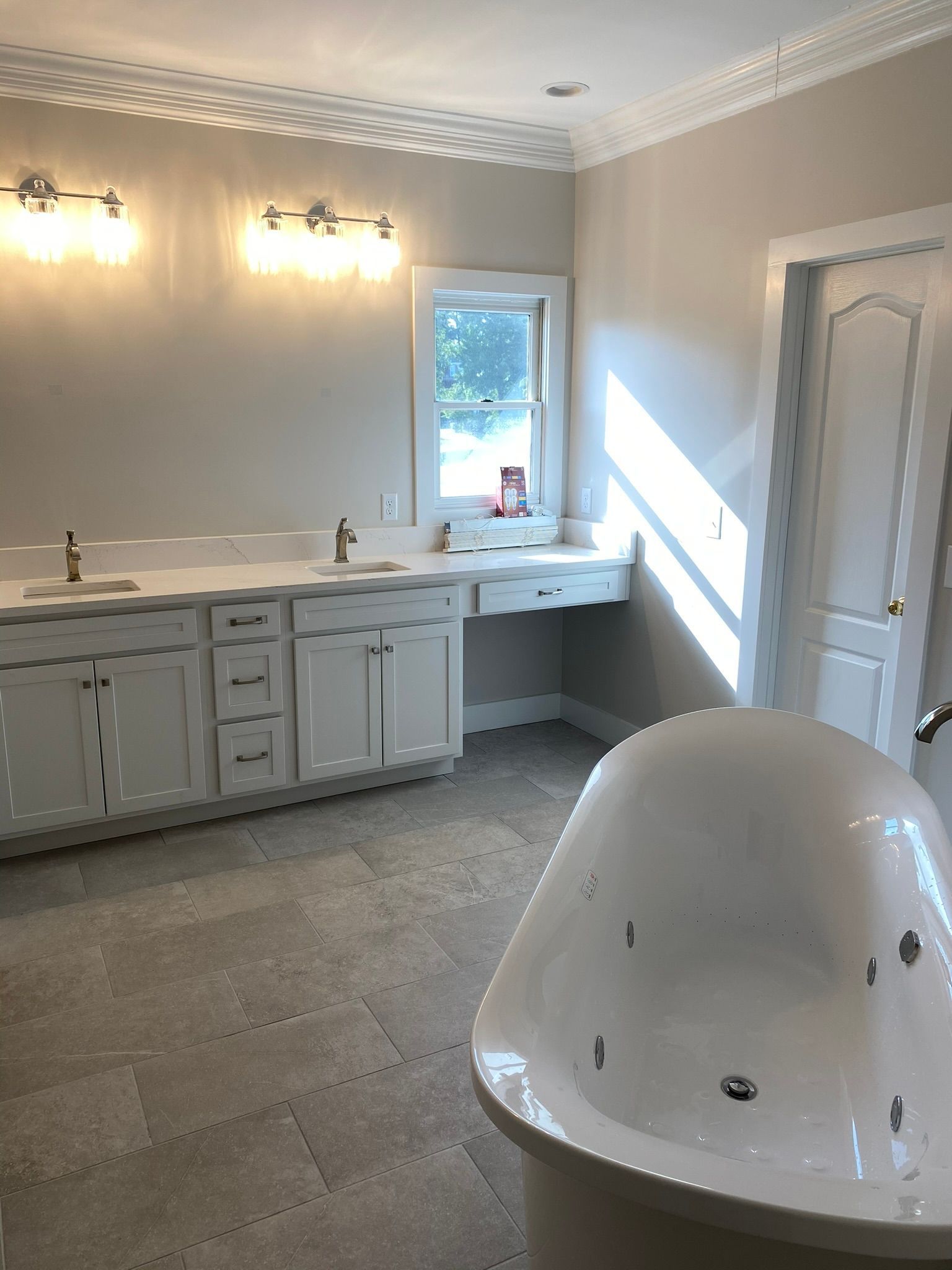 A bathroom with a tub , sinks and cabinets