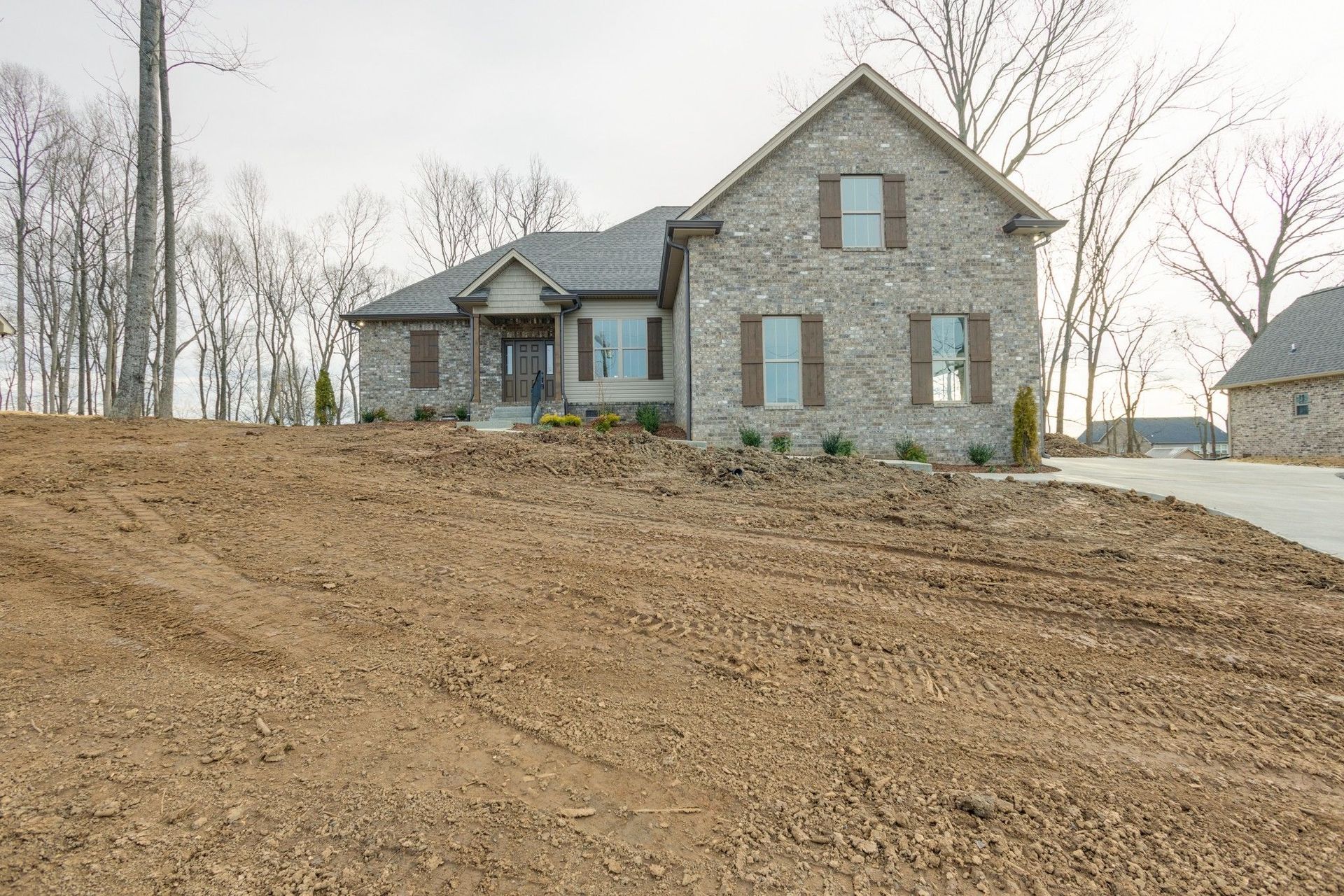 A large brick house is sitting on top of a dirt hill.