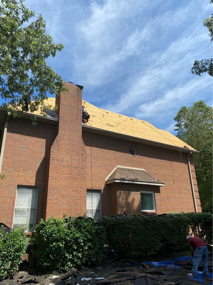 A man is working on the roof of a brick house.