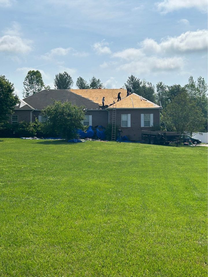 A house with a roof that is being installed in a grassy field.