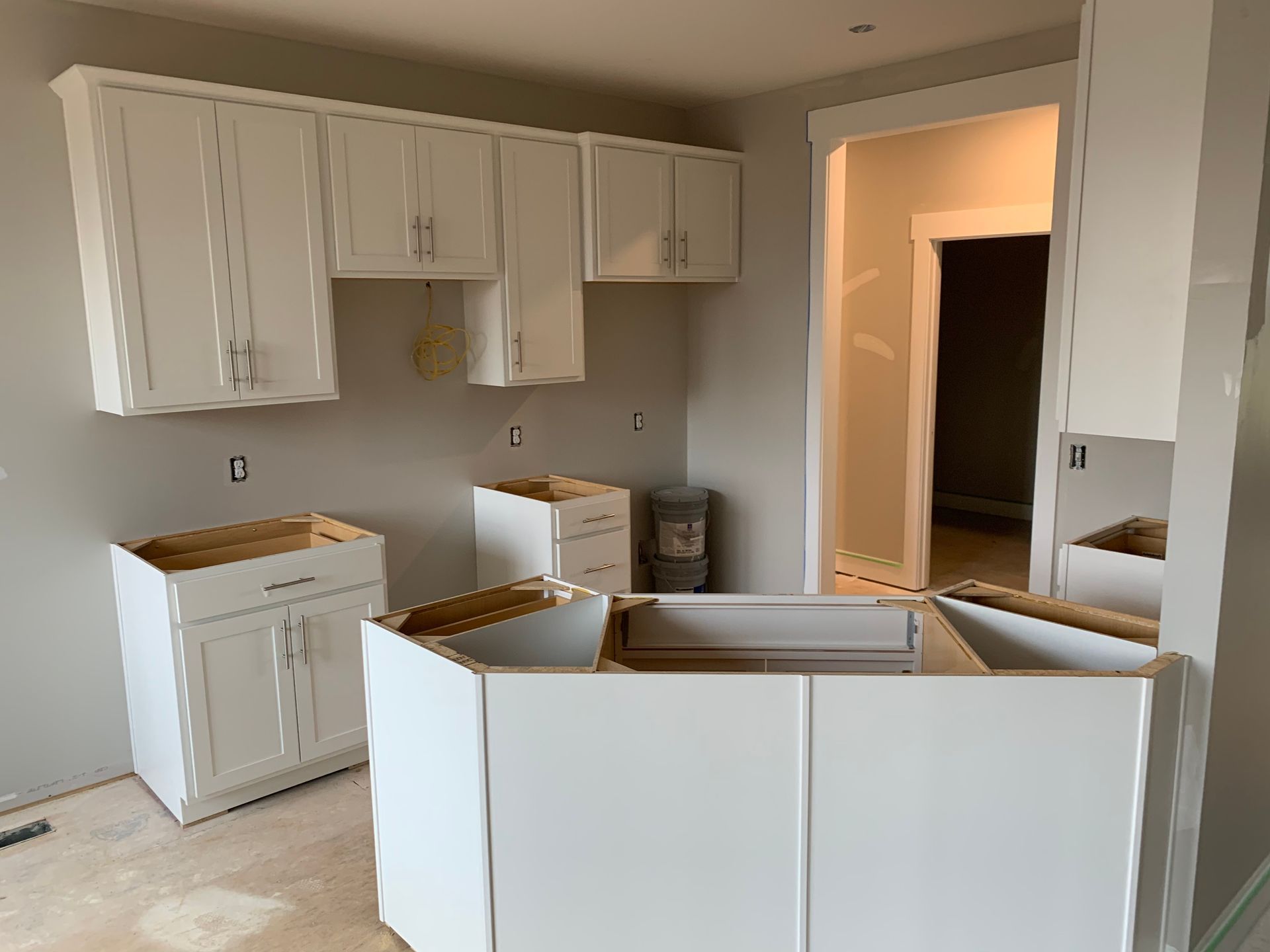 A kitchen with white cabinets being built in a house.