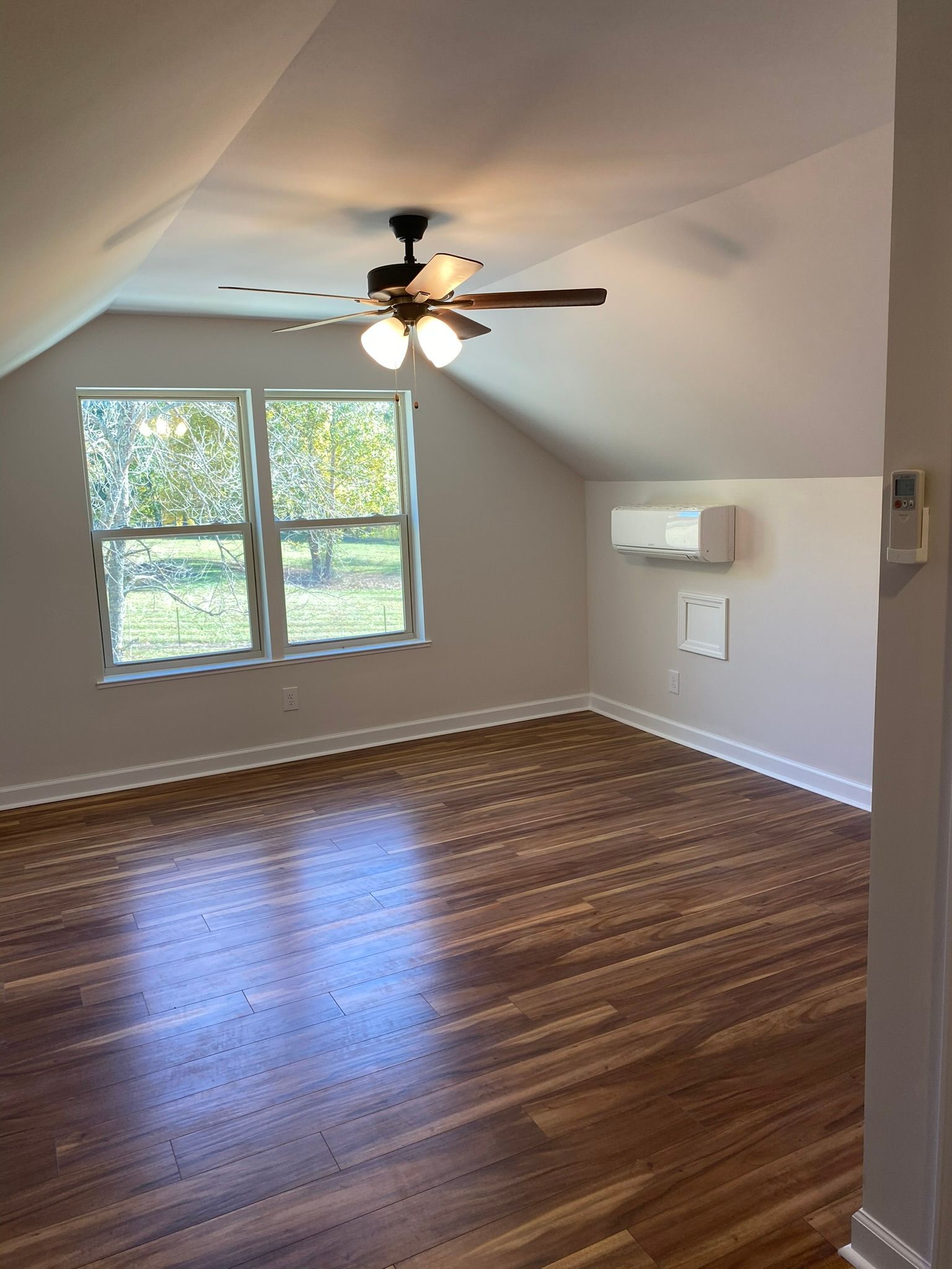 An empty living room with hardwood floors and a ceiling fan.