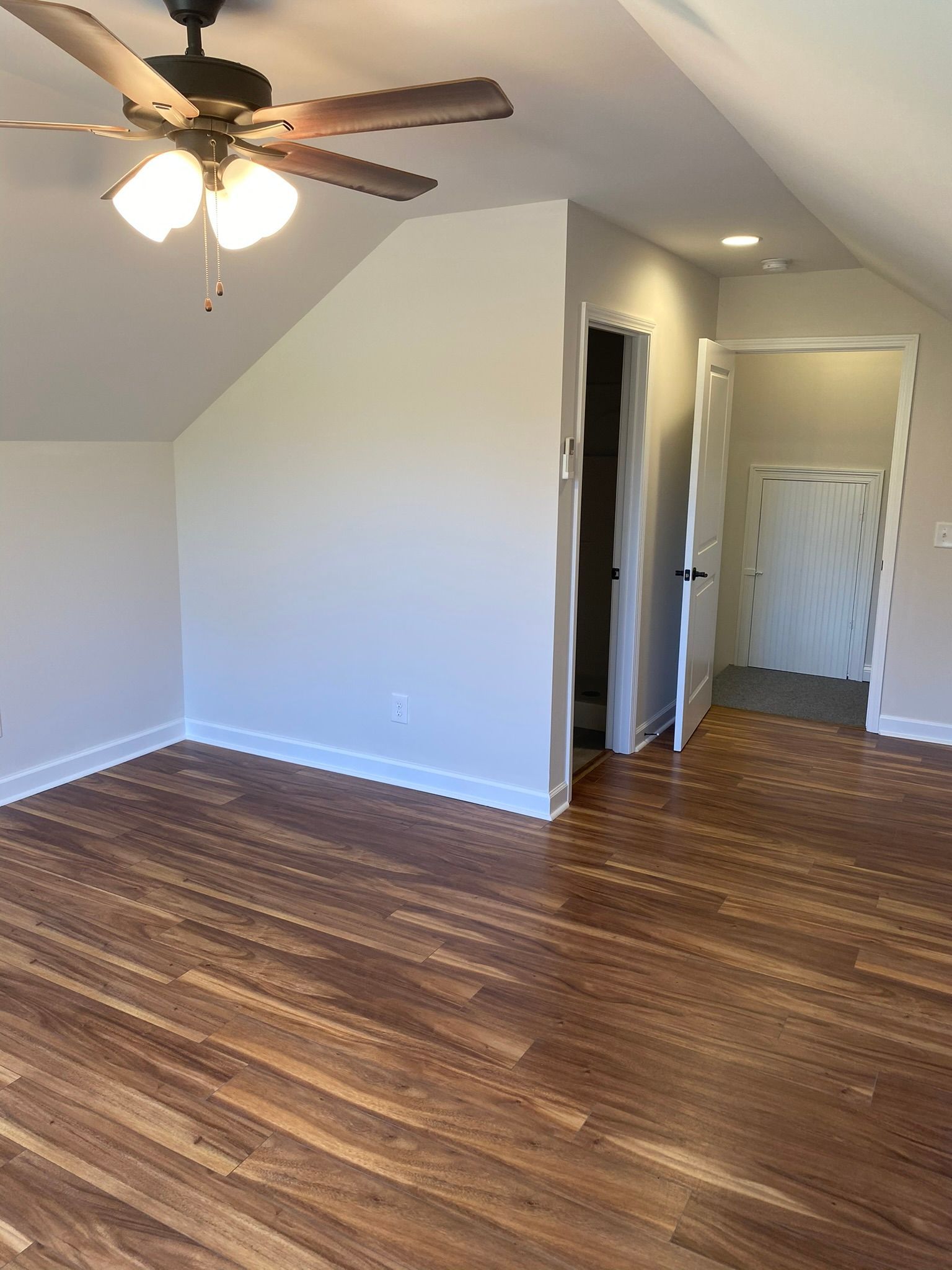 An empty room with hardwood floors and a ceiling fan.