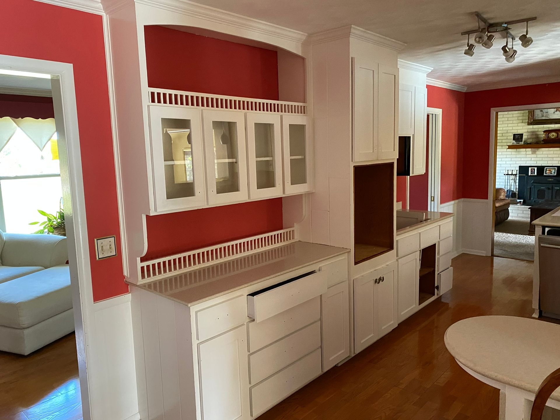 A kitchen with white cabinets and red walls