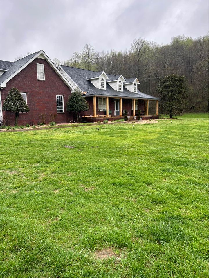 A large brick house with a large lawn in front of it.