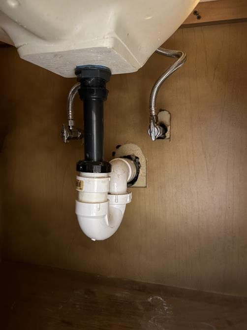 a man is fixing a sink pipe with water coming out of it